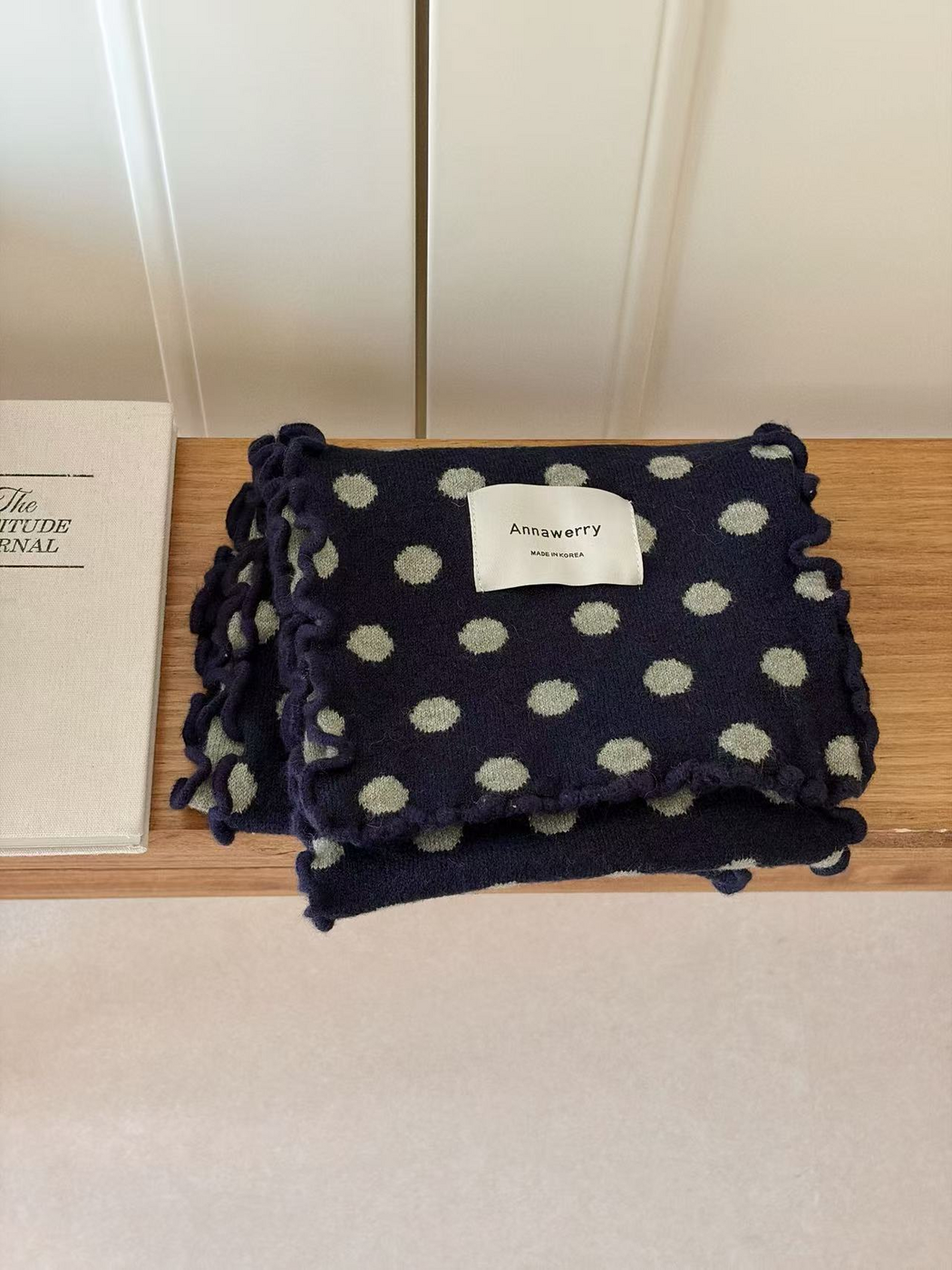 Navy scarf with light gray polka dots and ruffled edges, folded view