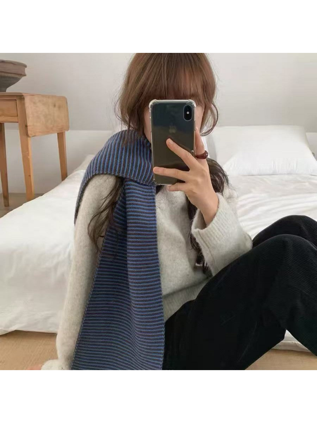 Blue striped scarf draped over one shoulder, seated view