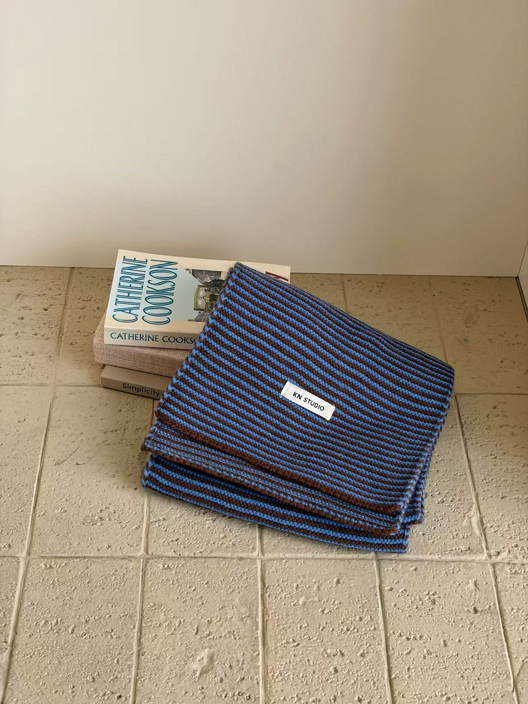 Blue striped knit scarf folded with its KN STUDIO label visible