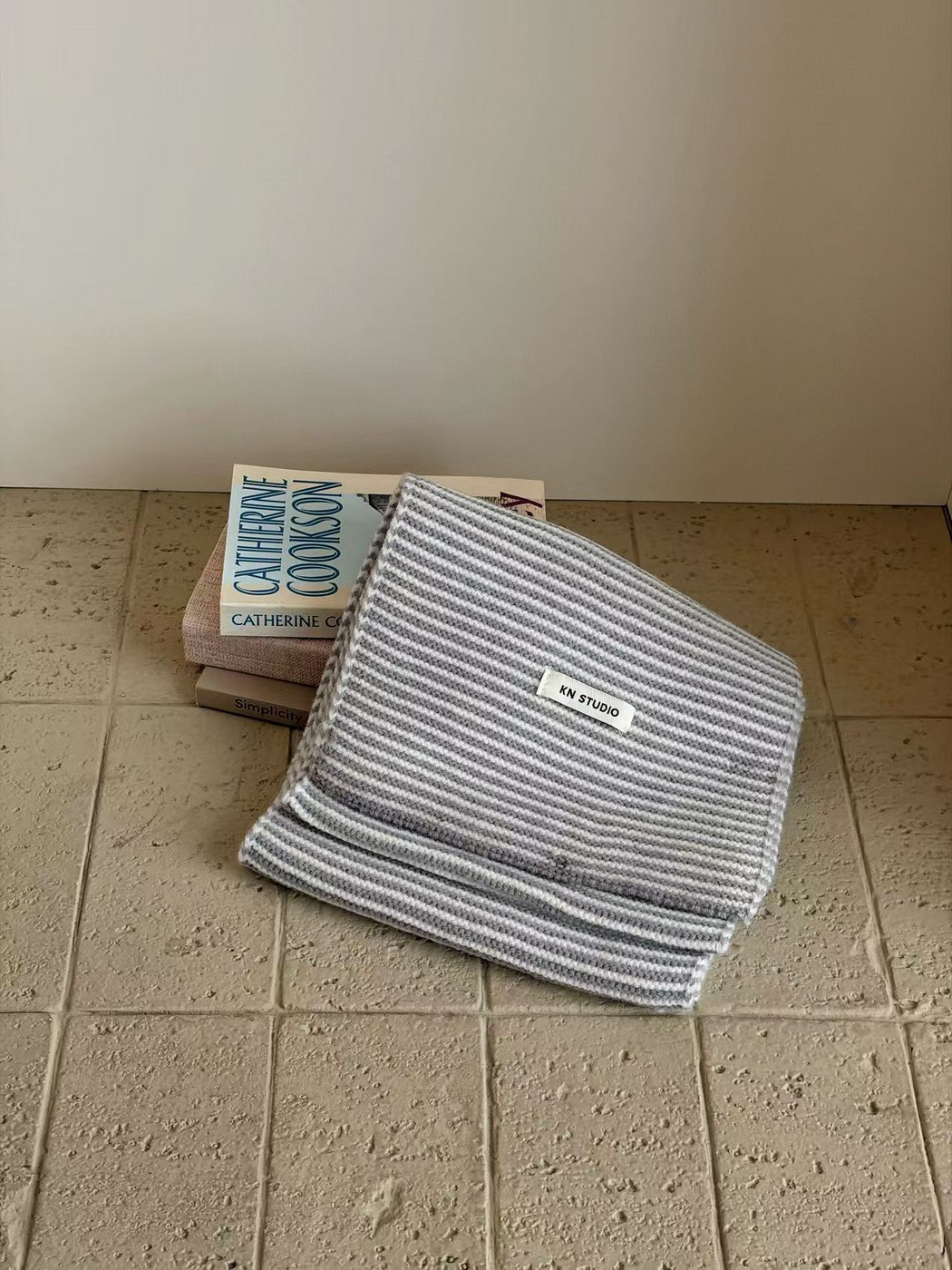 Gray striped knit scarf folded with its KN STUDIO label visible