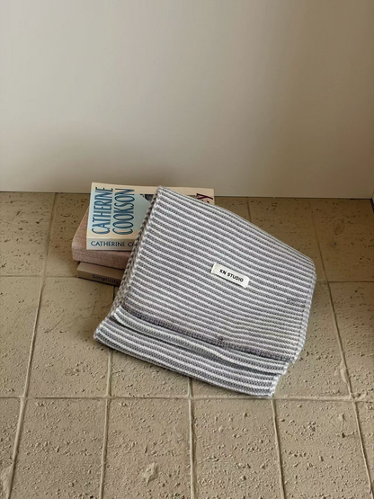 Gray striped knit scarf folded with its KN STUDIO label visible