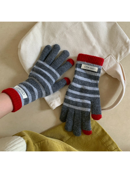 Gray striped gloves with red cuffs, one worn and one resting on a tote bag