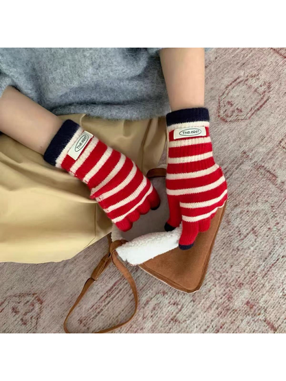 Red gloves with white stripes and navy cuffs worn beside a brown bag