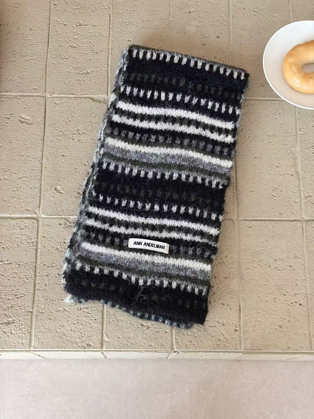 Black scarf folded lengthwise, with white dash rows, paired white stripes and gray bands