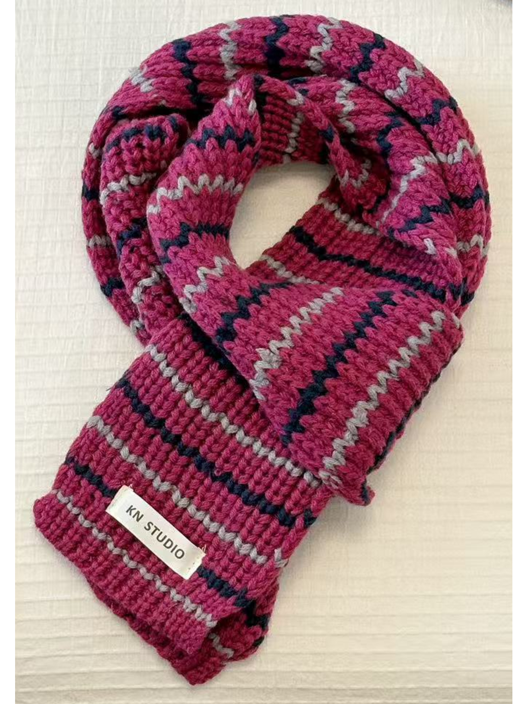 Fuchsia knit scarf with navy and gray stripes, looped with the KN STUDIO label visible