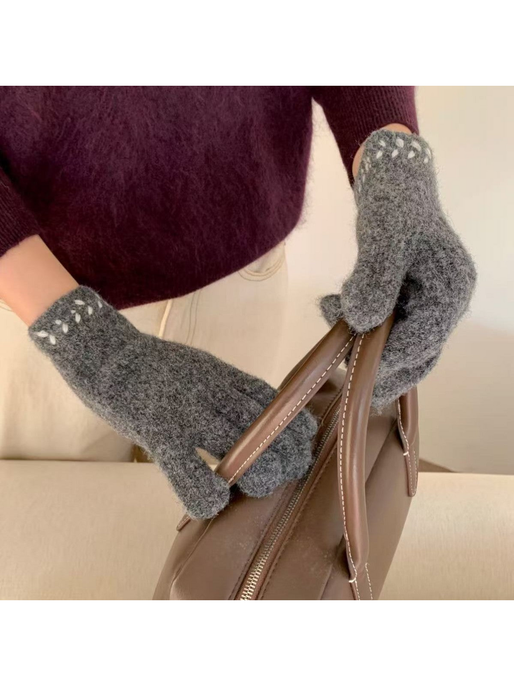 Gloves with contrasting cuff embroidery holding a brown handbag
