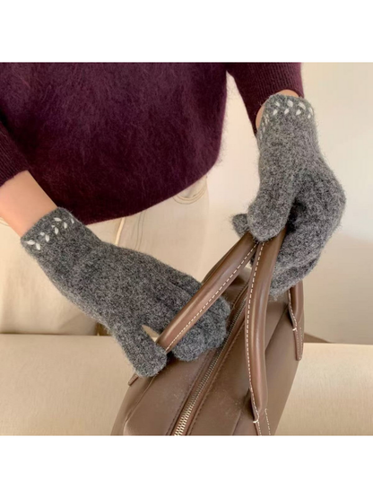 Gloves with contrasting cuff embroidery holding a brown handbag