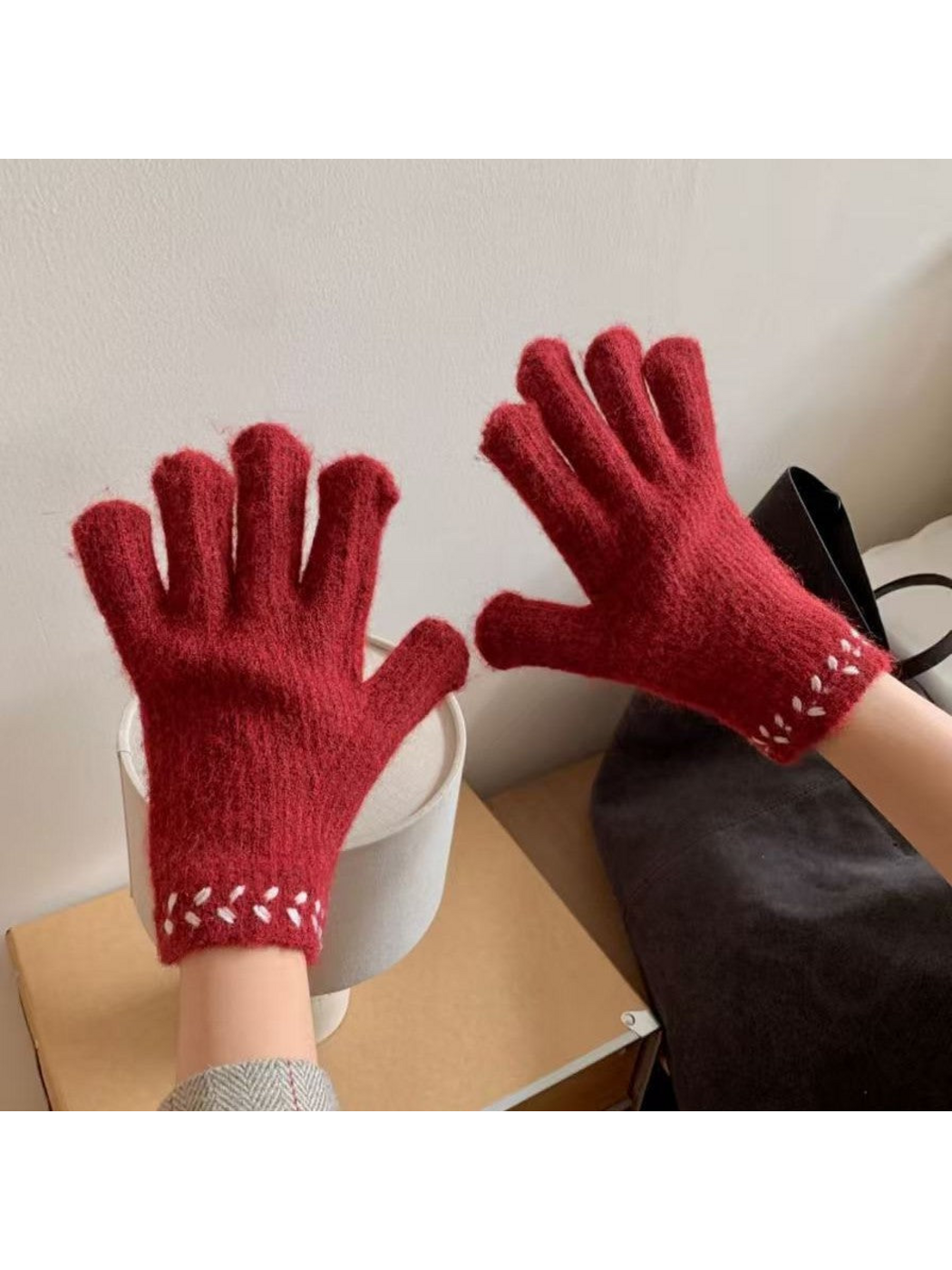 Gloves worn with fingers spread, showing contrasting cuff embroidery