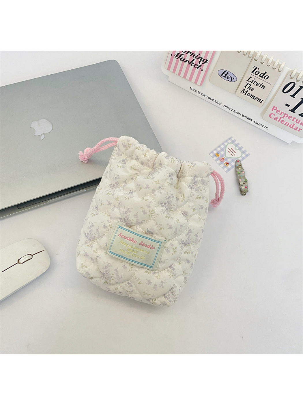 Purple floral drawstring pouch with curved quilting and pink drawcords, front view
