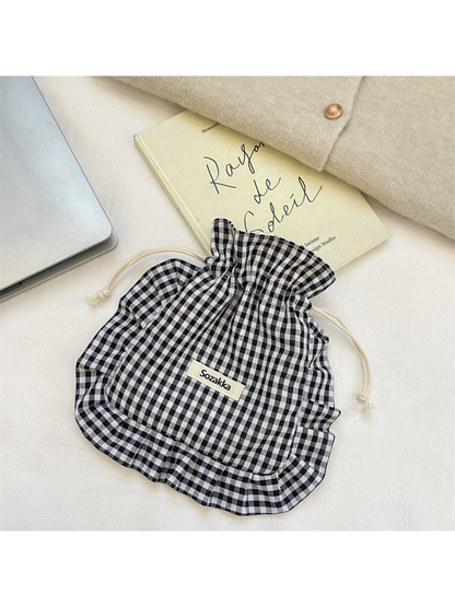 Black gingham drawstring pouch with cream cords and ruffled border, front view