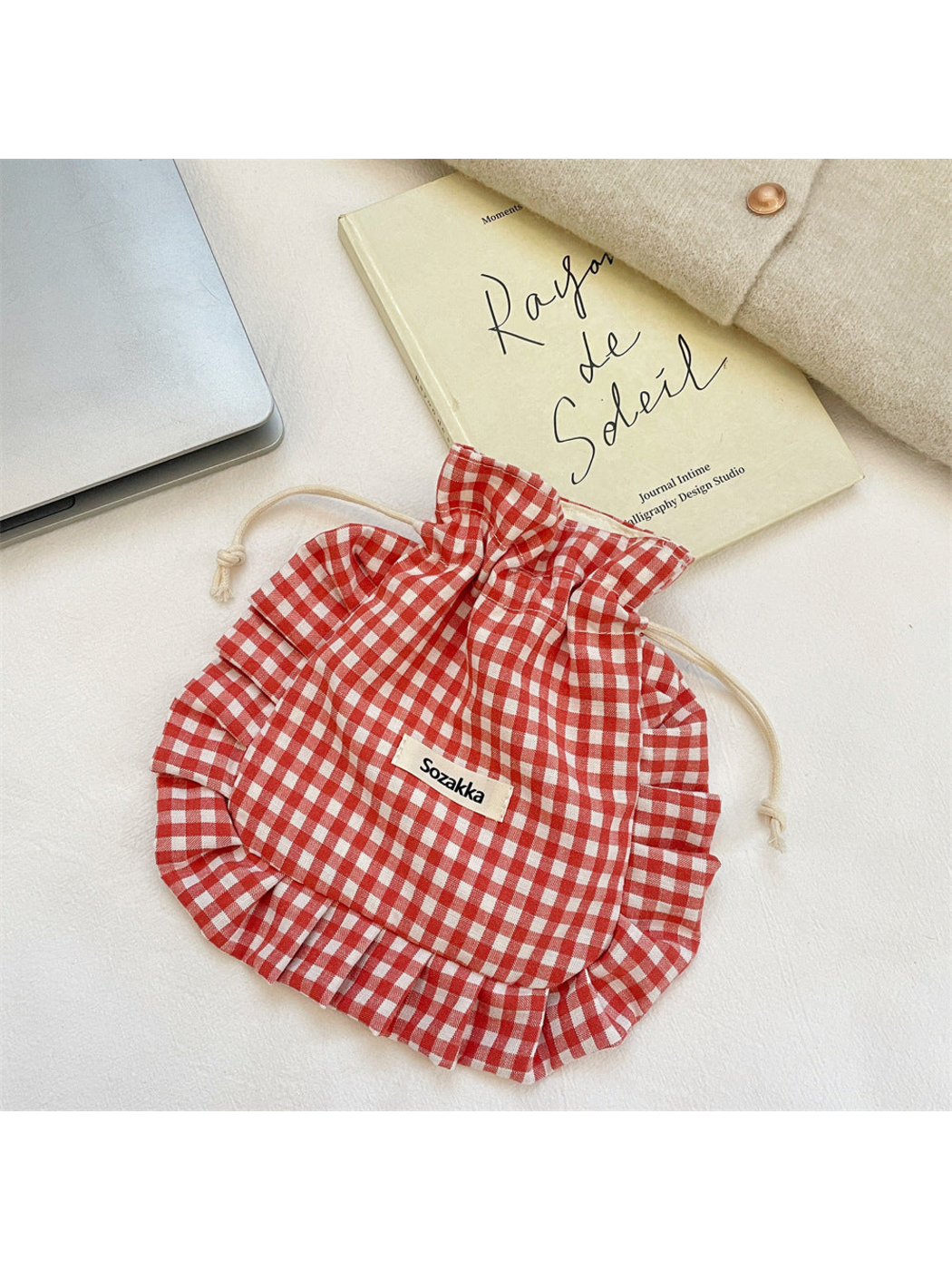 Red gingham drawstring pouch with cream cords, laid flat