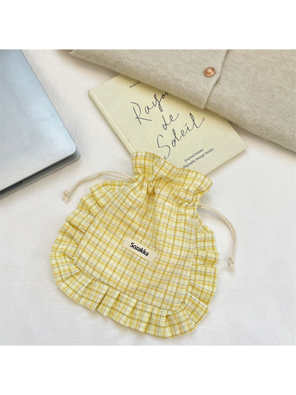 Yellow plaid drawstring pouch with ruffled trim, laid flat