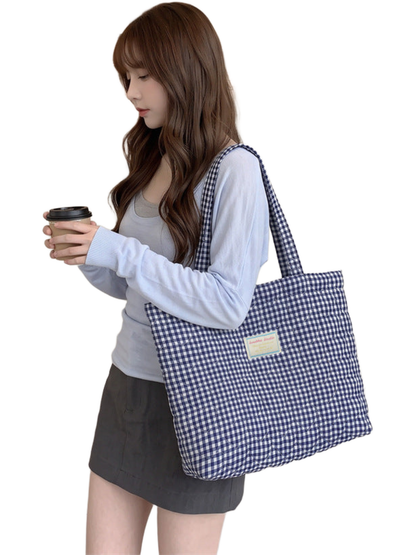 Blue gingham tote with heart-shaped quilting carried over the shoulder