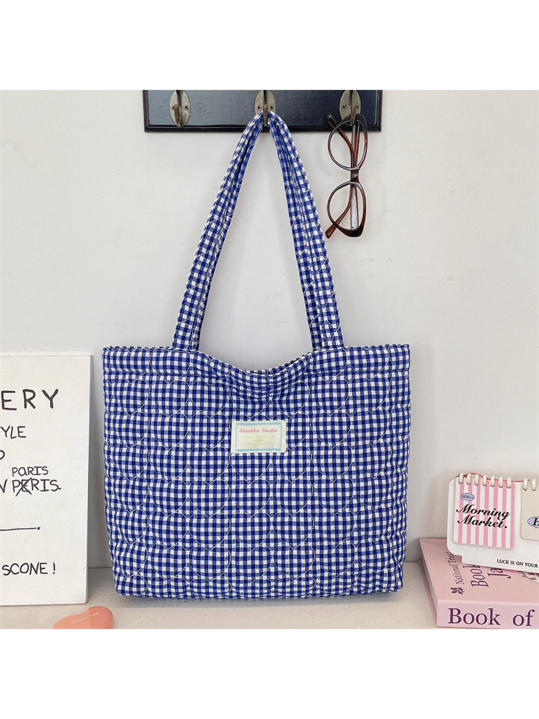 Blue gingham tote with heart-shaped quilting hanging by its long handles