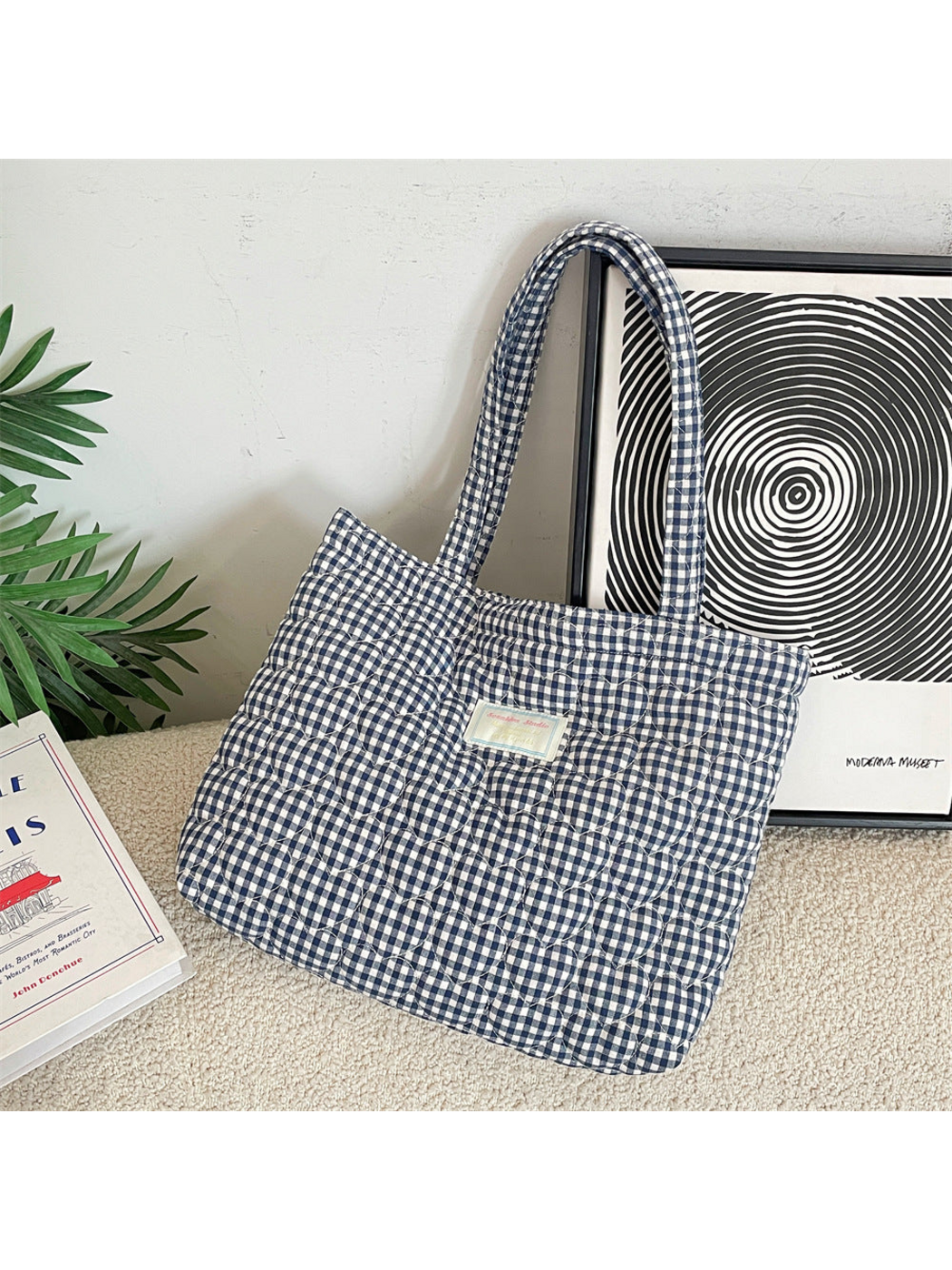 Navy gingham tote with heart-shaped quilting leaning against framed artwork