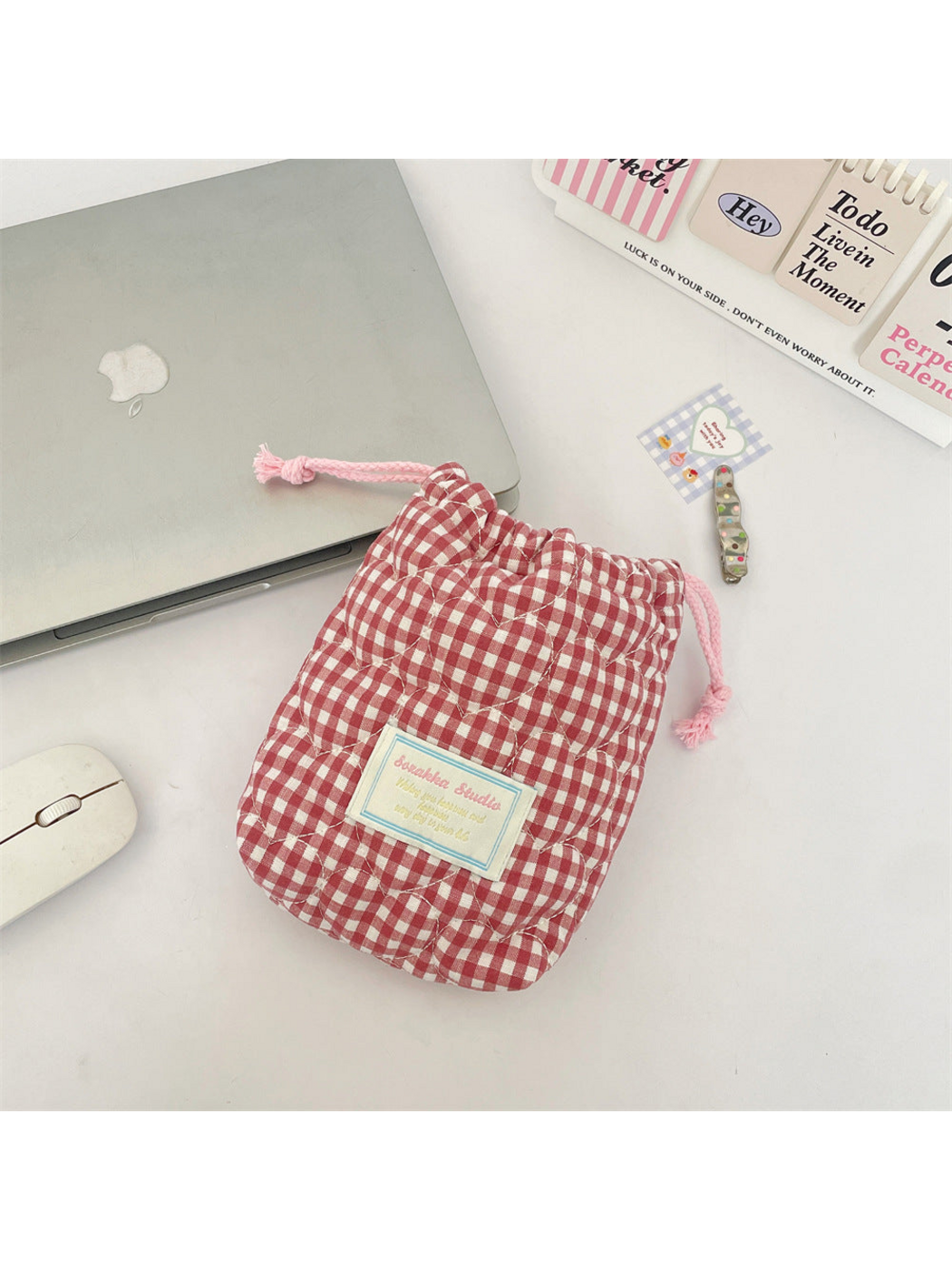 Pink gingham drawstring pouch with heart-shaped quilting, knotted pink cords and a front label