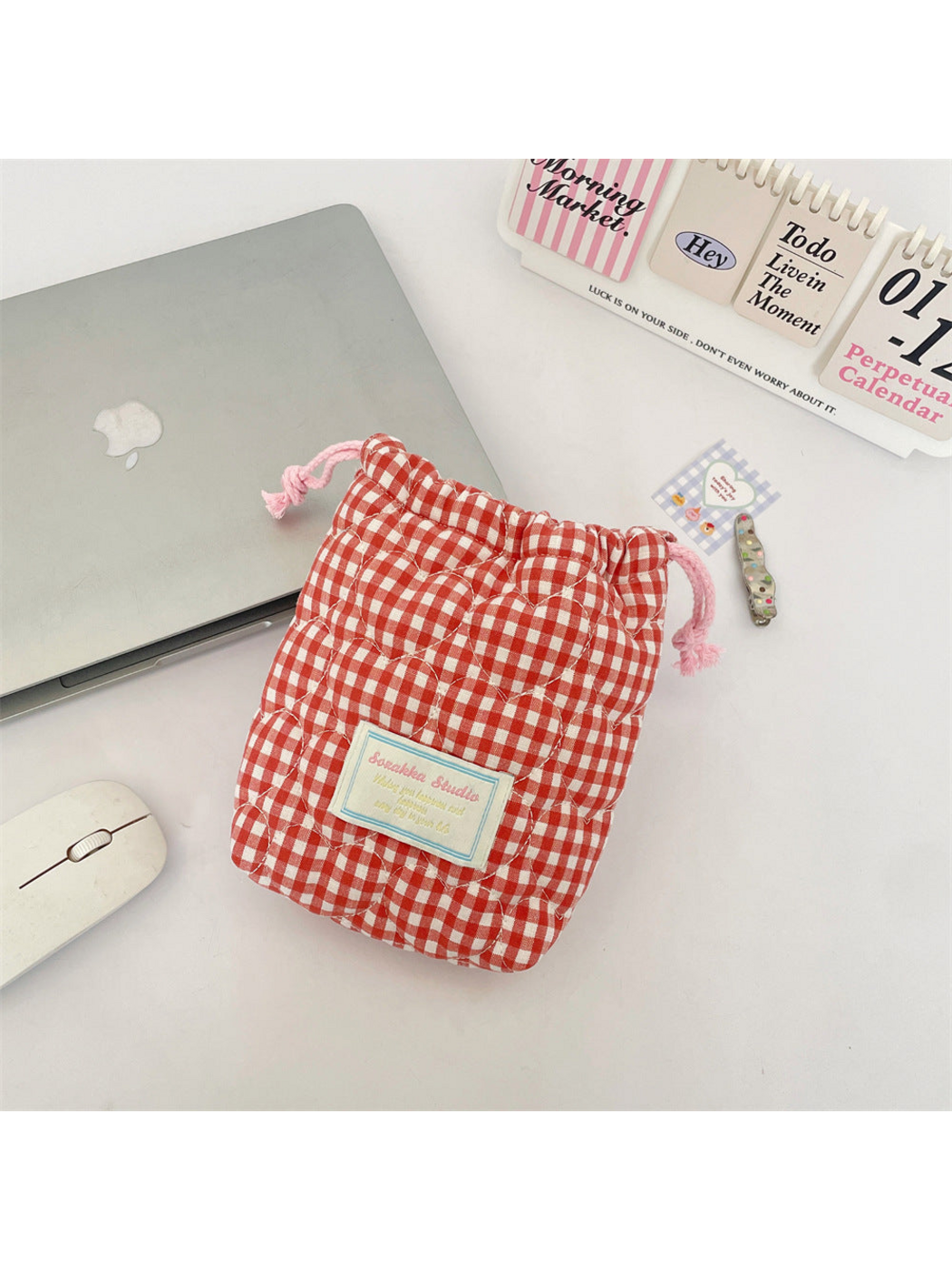 Red gingham drawstring pouch with heart-shaped quilting, pink drawstrings and a blue-bordered front label