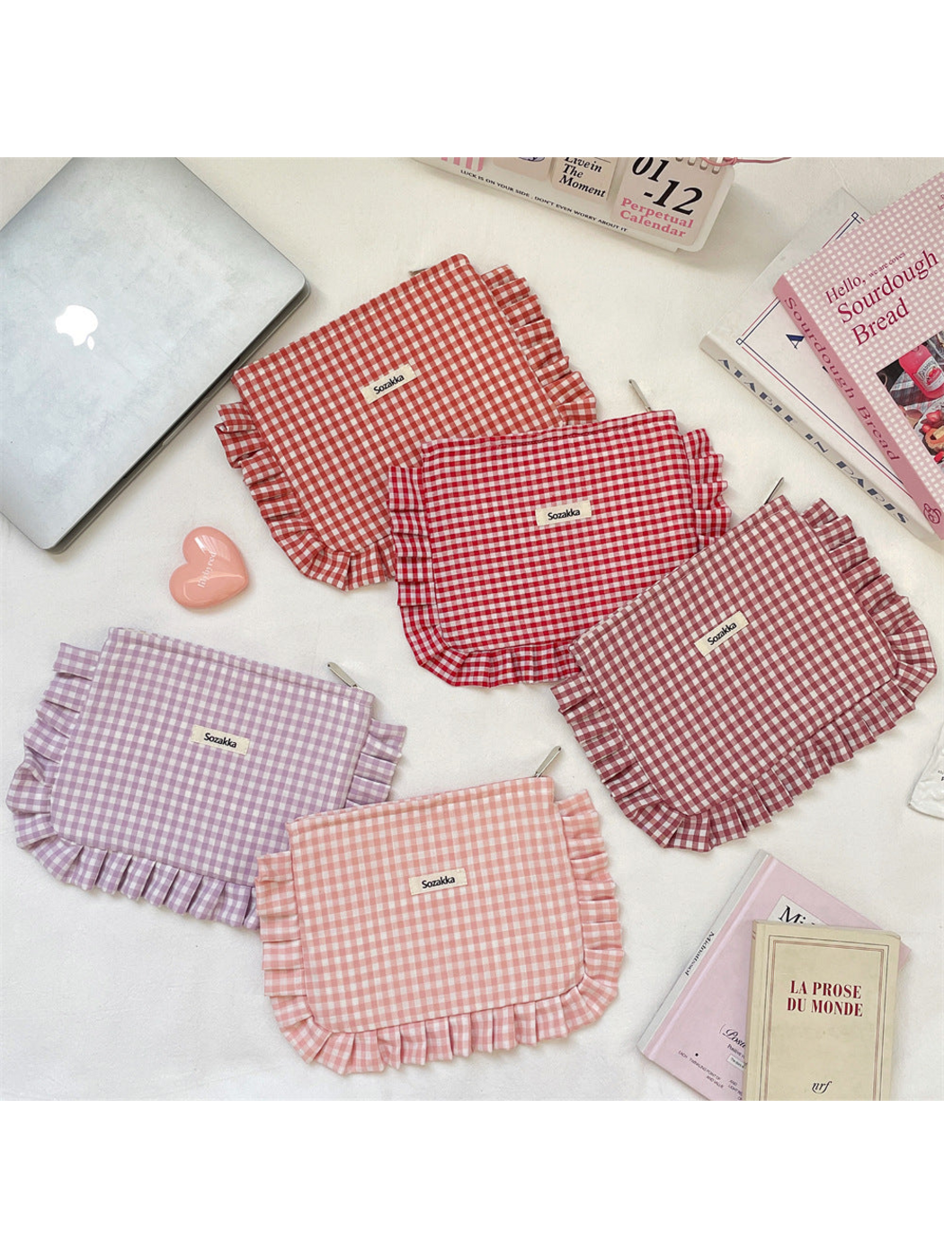 Five gingham makeup pouches with ruffled edging arranged on a light surface