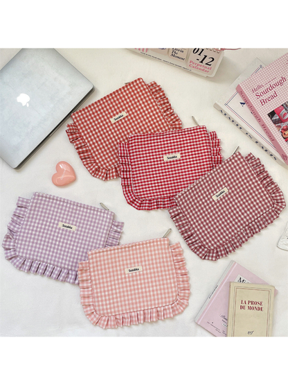 Five gingham makeup pouches with ruffled edging arranged on a light surface