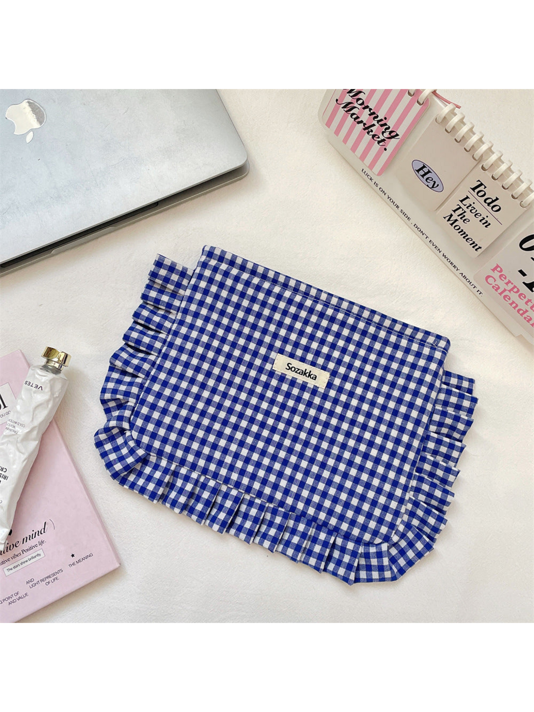 Blue gingham cosmetic pouch with white checks and ruffled trim, flat front view