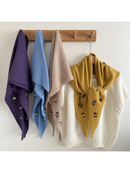 Embroidered knit scarves hanging beside a scarf tied over a white top