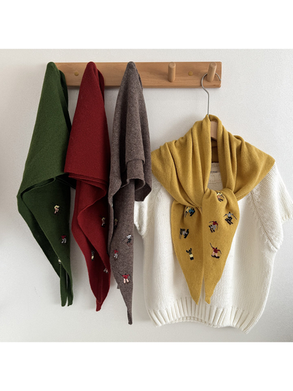 Hanging knit scarves with embroidered figures beside a tied scarf