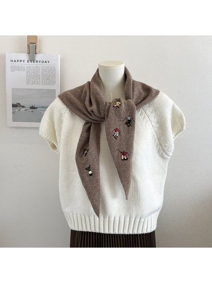Light Coffee knit triangle scarf with embroidered figures, tied on a mannequin
