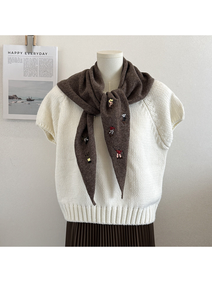 Brown knit triangle scarf with embroidered figures, tied on a mannequin