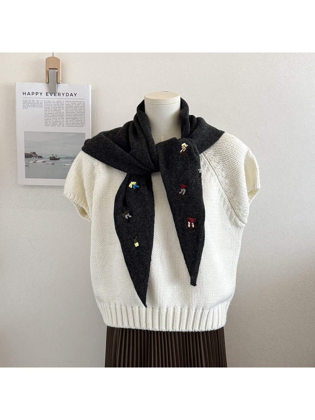 Black Gray knit triangle scarf with embroidered figures, tied on a mannequin