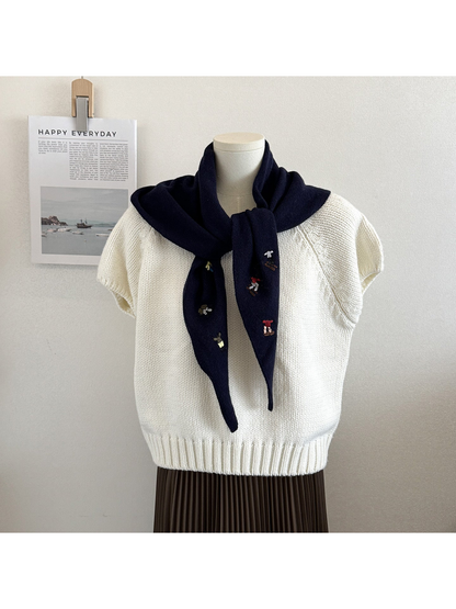 Navy knit triangle scarf with embroidered figures, tied on a mannequin