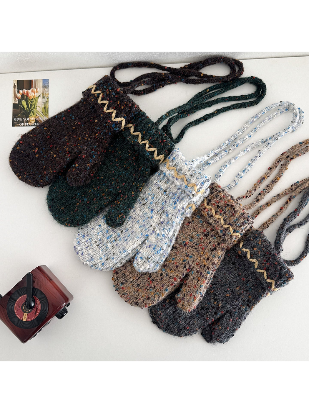 Overlapping flecked mittens with cream zigzag cuffs and extended connecting cords