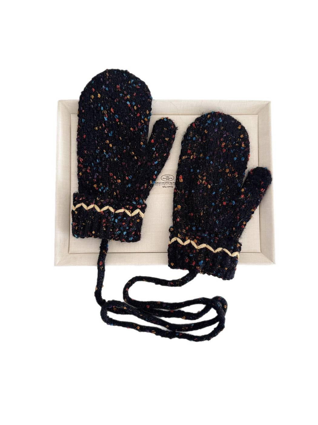 Dark flecked mittens with cream zigzag cuffs and a long connecting cord