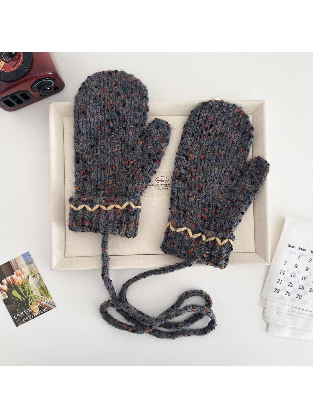 Gray flecked mittens with cream zigzag cuffs and a connecting cord