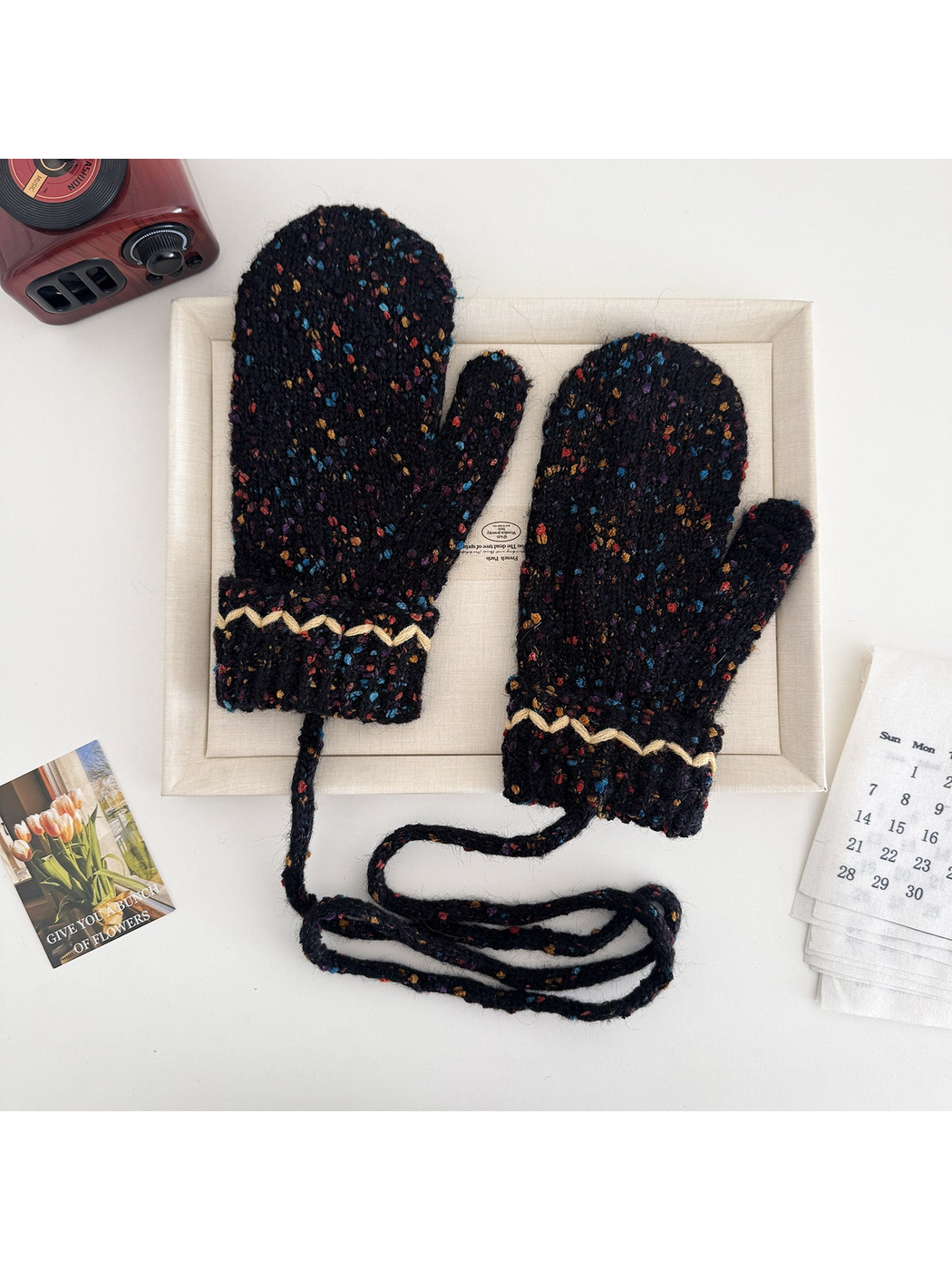 Black flecked mittens with cream zigzag cuffs and a connecting cord