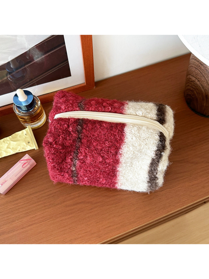 Red makeup bag with broad red and ivory blocks and narrow dark stripes