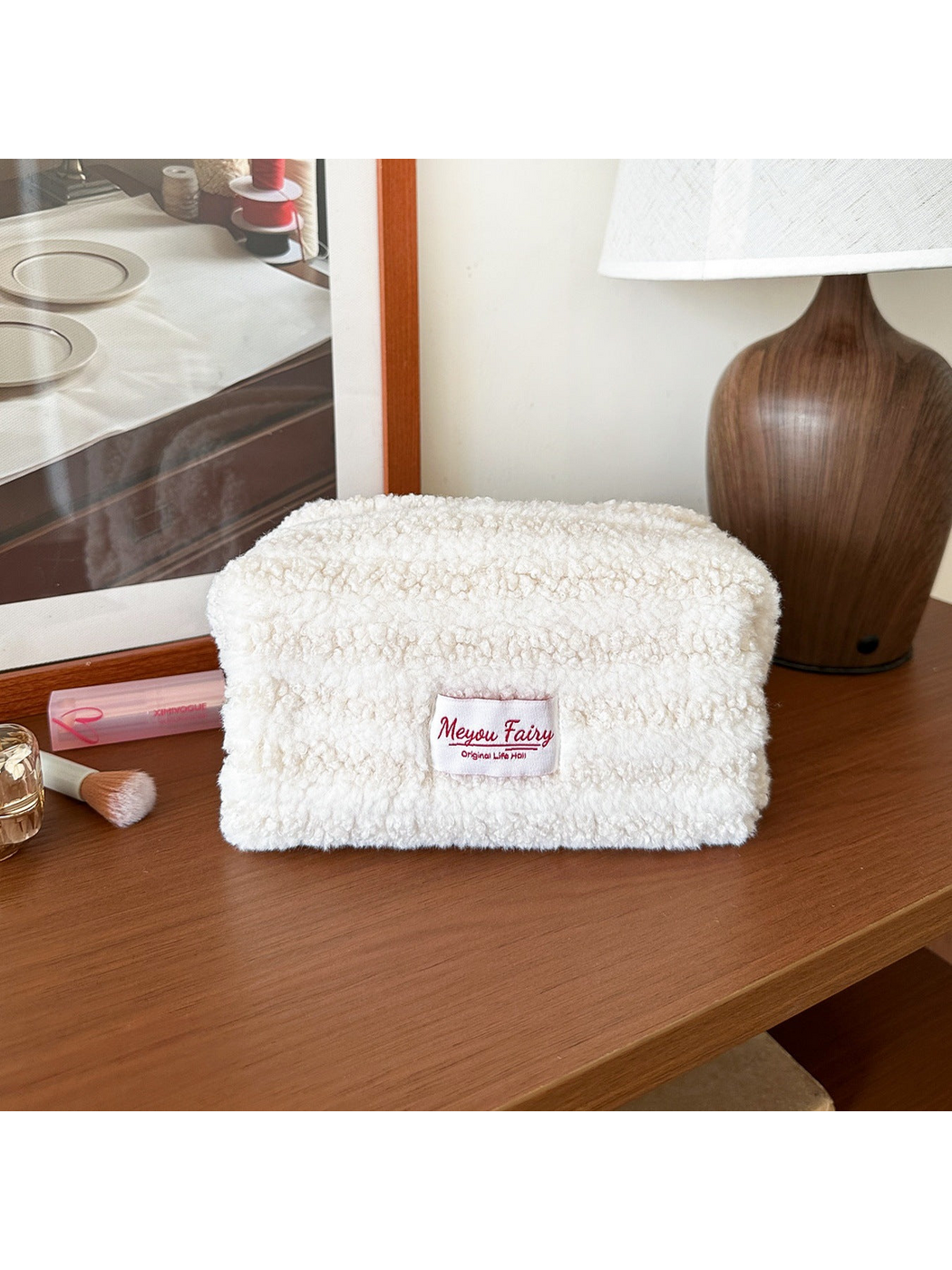 Ivory cosmetic pouch with horizontal texture bands and a front label