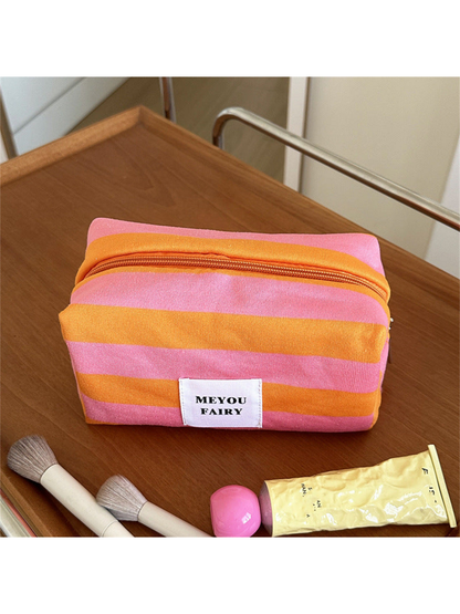 Orange striped makeup bag with pink stripes and a white front label