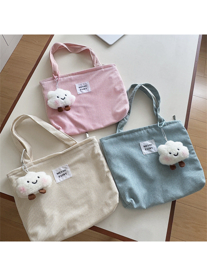 Pink, Beige and Blue ribbed tote bags with cloud charms on a tabletop
