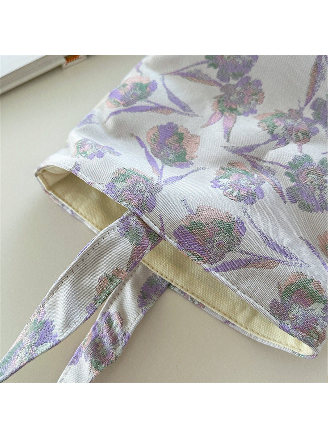 Close-up of the Purple bag's floral texture, loop handle attachment and pale interior