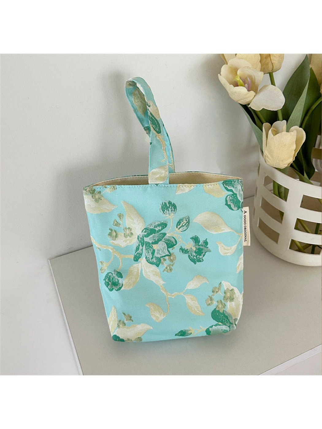 Turquoise floral bucket bag with loop handle and visible pale opening