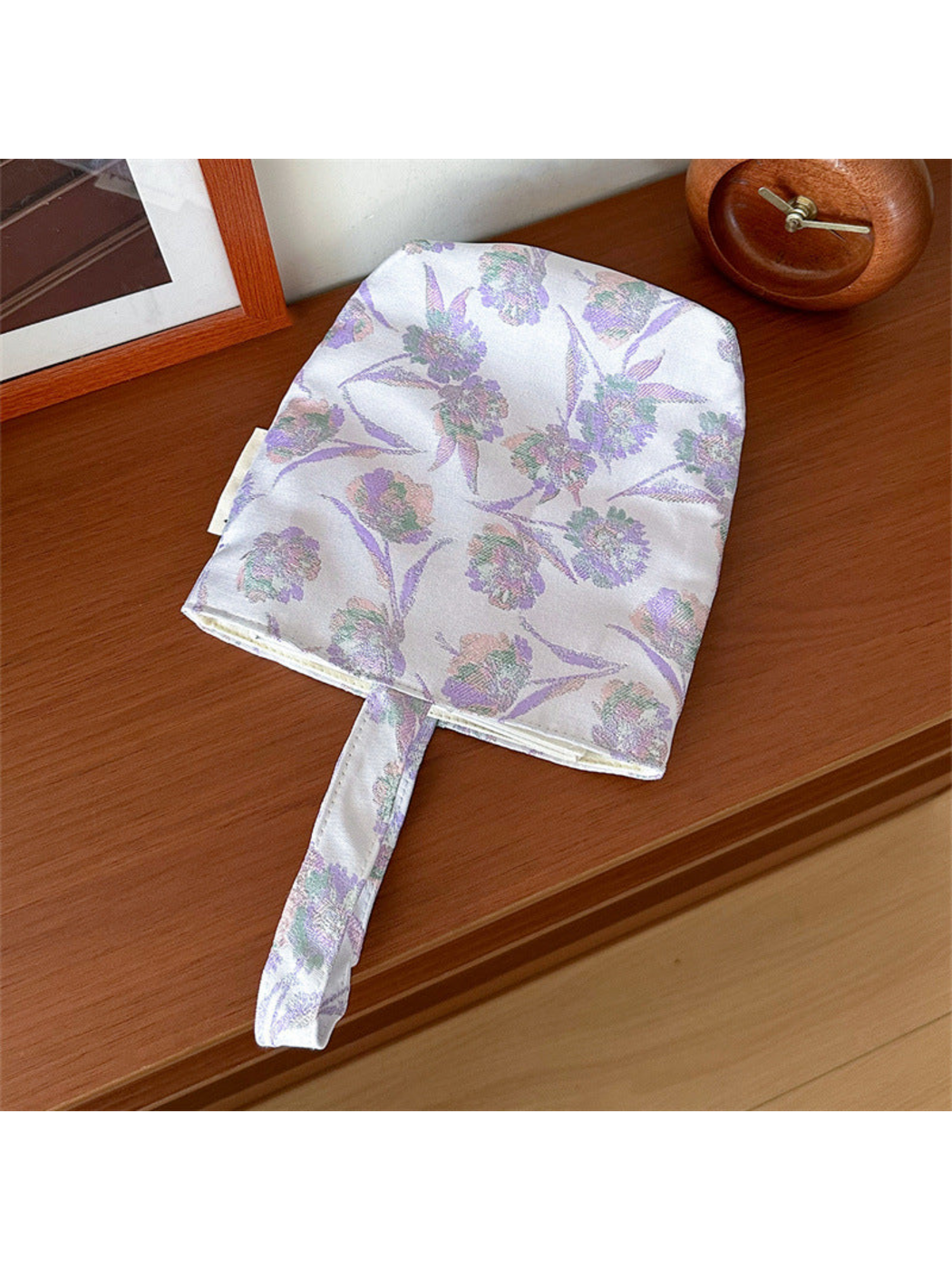 Purple floral bucket bag laid flat with its complete loop handle