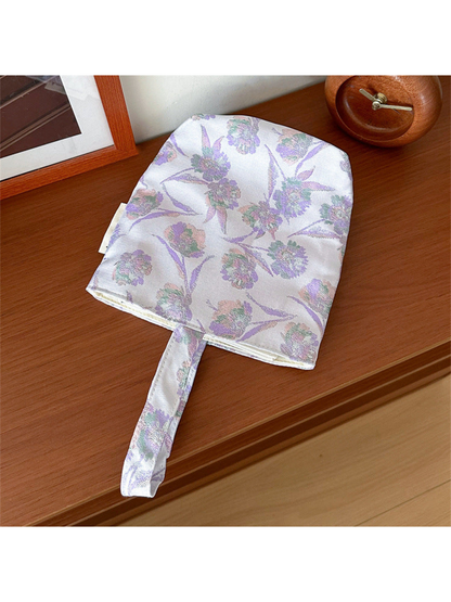 Purple floral bucket bag laid flat with its complete loop handle