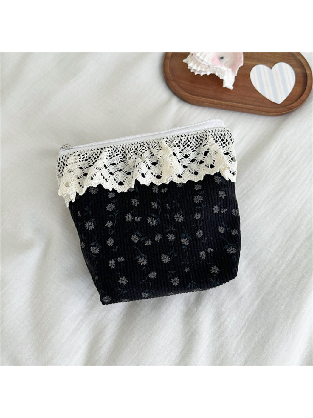 Black pouch with small gray flowers and scalloped ivory lace trim, front view