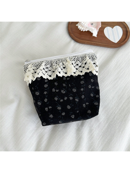 Black pouch with small gray flowers and scalloped ivory lace trim, front view