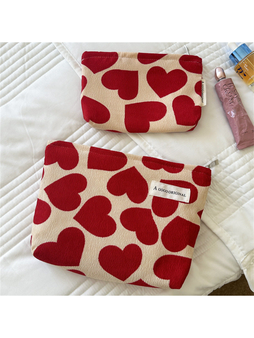 Large and Small cream pouches with red hearts laid flat on white bedding