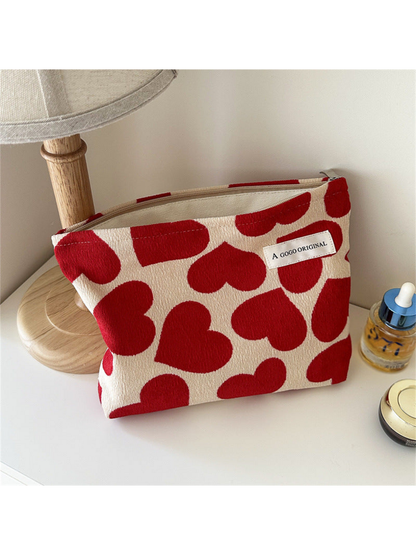 Large heart-pattern cosmetic pouch standing upright with its cream interior visible