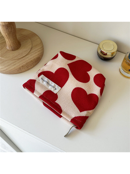 Trapezoid cream pouch with red hearts and a white front label, viewed from above