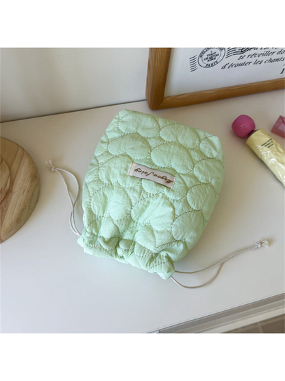 Mint heart-quilted drawstring pouch with cream cords on a tabletop