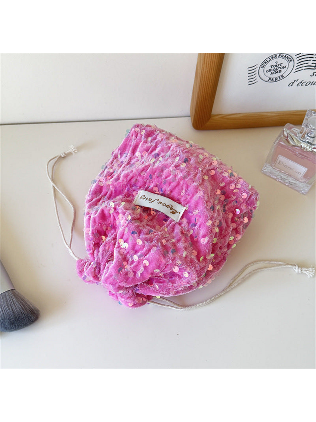Pink sequined drawstring pouch lying loosely gathered on a tabletop