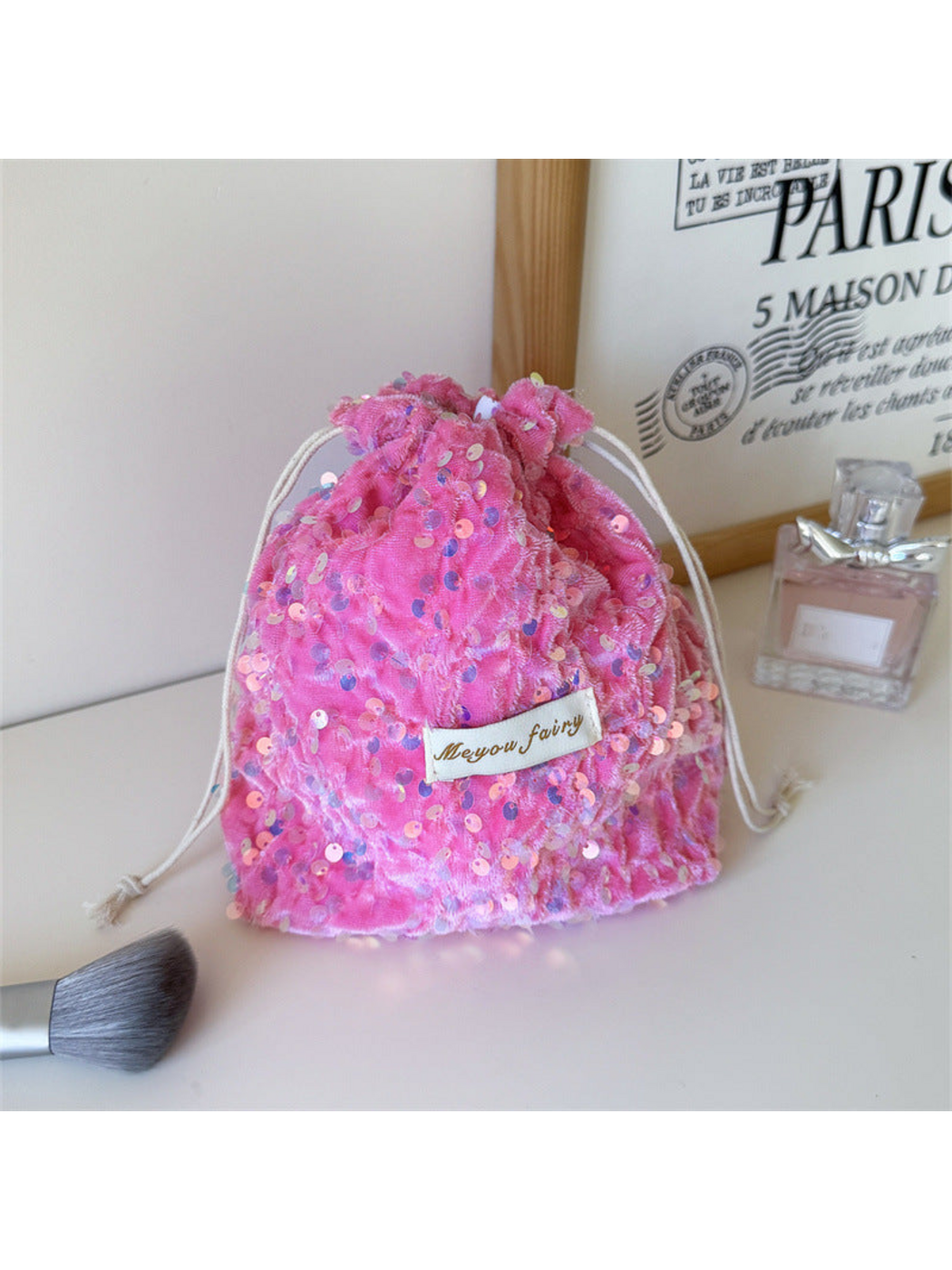 Pink sequined drawstring pouch standing upright with its gathered opening visible